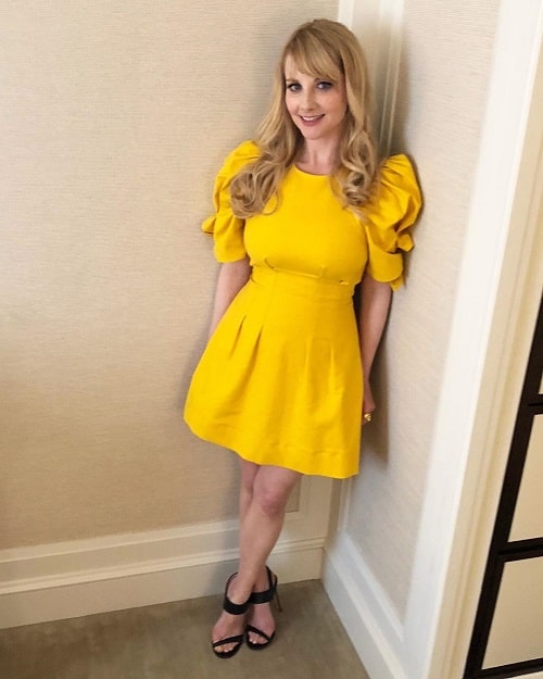 A picture of Melissa Rauch looking beautiful in yellow dress.